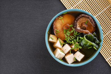 Japanese miso soup with shiitake mushrooms, tofu cheese, fresh onions and wakame seaweed. Top view.