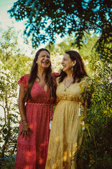 Senior woman looking at daughter laughing while standing by green plants at campsite during glamping weekend