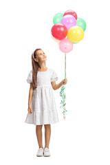 Fototapeta na wymiar Full length portrait of a girl in a white dress holding a bunch of balloons and looking up