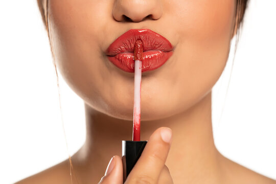 Close up of a young beautiful woman applies lip gloss