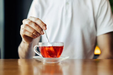 man drinking aromatic tea during lunch break in cafe, young man enjoying delicious hot drink holding cup