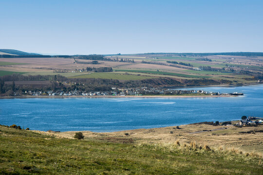 The small Scottish highland village of Cromarty nestles at the shore of the Black Isle with the Cromarty Firth in the middle of the image. The dunes of Nigg are in the foreground of the picture.