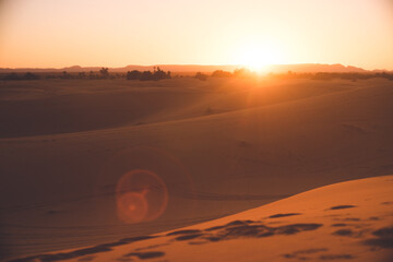 Fototapeta na wymiar モロッコ メルズーガ サハラ砂漠砂丘のオアシスに沈む夕陽