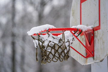 Basketball hoop net after snowstorm filled with snow in winter park, Ukraine. Winter basketball...