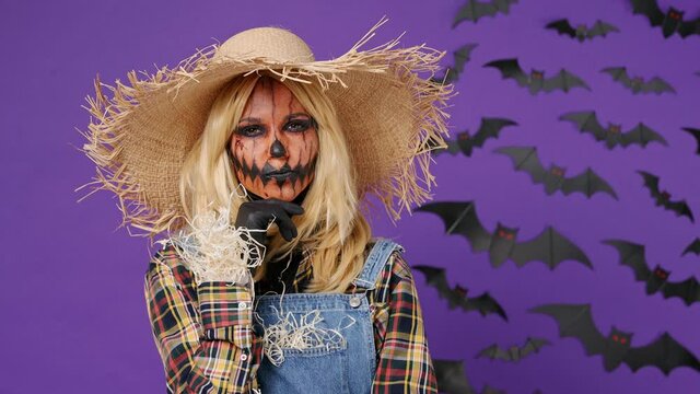 Insighted smart young woman with Halloween makeup mask wears straw hat scarecrow costume looks around thinks comes up with ideas raised finger isolated on plain dark purple background studio portrait