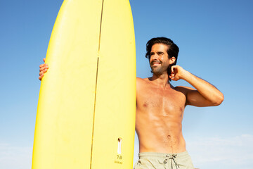 Handsome man with surfboard. Surfer taking a break on the beach.