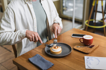 partial view of man holding cutlery near lemon tart on plate