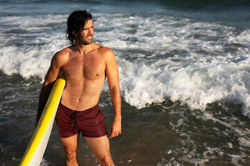 Handsome man with surfboard. Surfer taking a break on the beach.