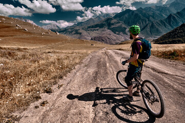 Mountain biking in Elbrus. Cyclist on the top of a hill and enjoying view of the mountains. MTB bicycle rider standing at cliff.