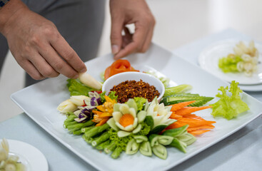Chef carves patterns on cabbage and other vegetables and fruits for a beautiful table decoration