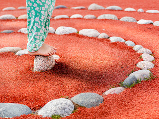 Kind balanciert auf Steinen. Gesunde Übung für Füße. Kind übt Gleichgewicht. Child balances on stones. Healthy exercise for feet. Child practices balance.