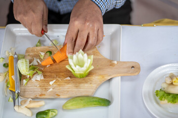 Chef carves patterns on cabbage and other vegetables and fruits for a beautiful table decoration