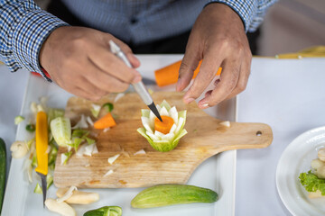 Chef carves patterns on cabbage and other vegetables and fruits for a beautiful table decoration