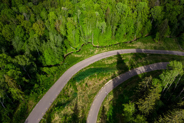 Asphalt road in a beautiful area. Aerial view of a roller ski trail winding through a forest...