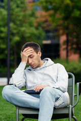 Obraz premium Frustrated startup owner businessman sit unhappy with closed laptop after getting email of business bankruptcy, money loss. Upset millennial remote entrepreneur bankrupt suffer from financial crisis