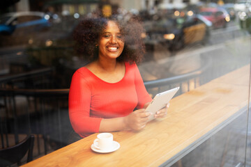 Businesswoman using tablet in cafe. Beautiful woman sitting in cafe, reading the news online.