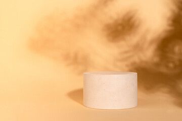 Concrete round cylinder on beige background with shadows and copy space. Empty showcase for product presentation. eco style and minimalism.
