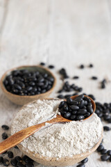 Ceramic bowls with black beans flour with a wooden spoon