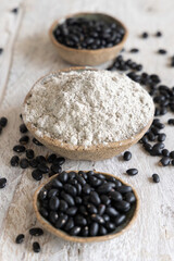 Ceramic bowls with black beans flour with a wooden spoon