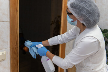 A woman in protective gloves and suit performing cleaning and disinfection in public areas.