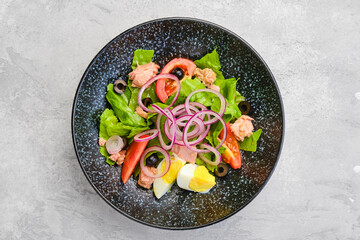 Top view of salad with lettuce, salmon, tomato, boiled egg and onion
