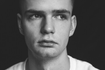 Young sad pensive guy in depression, portrait on black background