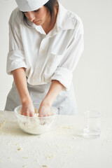 woman in chef's uniform sifts flour dough working in the kitchen