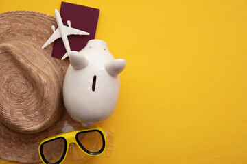 Saving for a summer vacation. Money piggy bank with holiday travel accessories