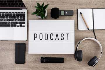 podcast concept - flat lay background, lightbox with podcast word on the table with laptop,...