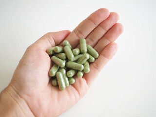 The green pill or andrographis paniculata is on a woman's hand. coronavirus issue and covid-19 prevention concept. closeup photo, blurred.