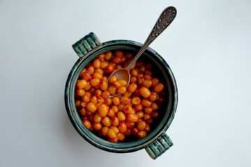 Sea buckthorn berries in a green round cup with a teaspoon