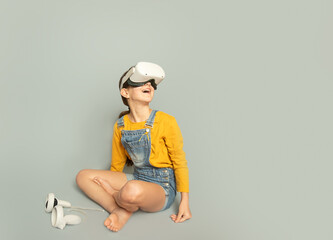 Child girl playing virtual reality over grey background, digital technology concept, innovative technologies