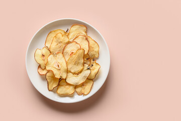 Fruits pear chips in white plate on a pink background. Healthy vegan snack. Top view.