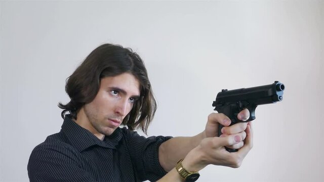 Young handsome man in dark shirt aiming the gun towards invisible target, 4k detail, gold watches