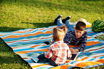 Family spending time together. Brother with sister painting outdoor in picnic blanket.
