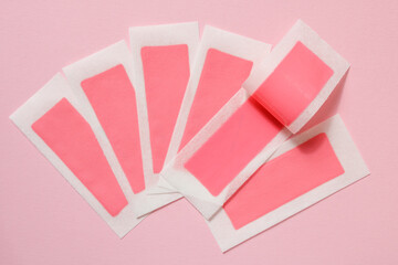 Pink wax strips for depilation on a pink background. Epilation, depilation, unwanted hair removal. Top view.
