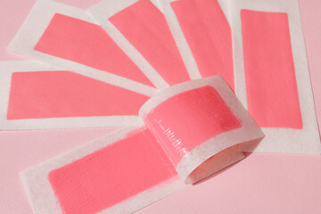 Pink wax strips for depilation on a pink background. Epilation, depilation, unwanted hair removal.