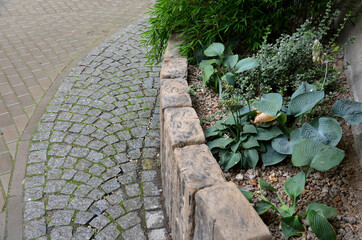 above the palisade of wooden sleepers are planted ornamental perennials and a very nice dwarf...