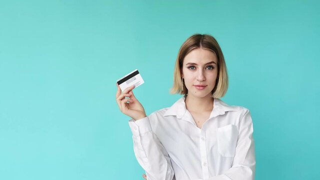 Secure payment. Bank service. Online transaction. Money safety. Confident pretty young woman demonstrating credit card with CVV code isolated on mint green empty space background.