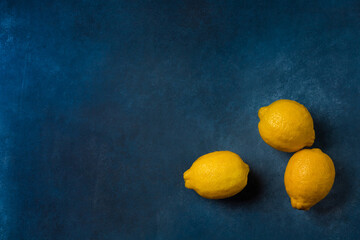 Three bright yellow citrus fruits on a blue background top view