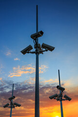 Many security cameras watching all around. CCTV equipment on dramatic sunset background