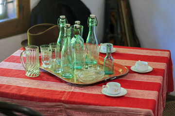 Vintage green bottles and glass cups on the table in old bar interior