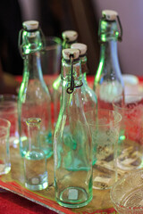 Empty green vintage bottles and crystal glasses on table