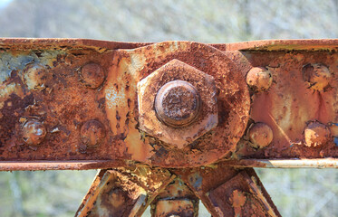 Front view of big old rusty bolt and nut on weathered background