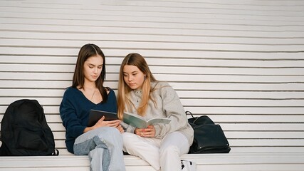 Two teenage students girls in university campus with books and laptop, back to school. People,...