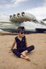 rocker boy a child in black clothes stands against the background of an abandoned plane on the beach
