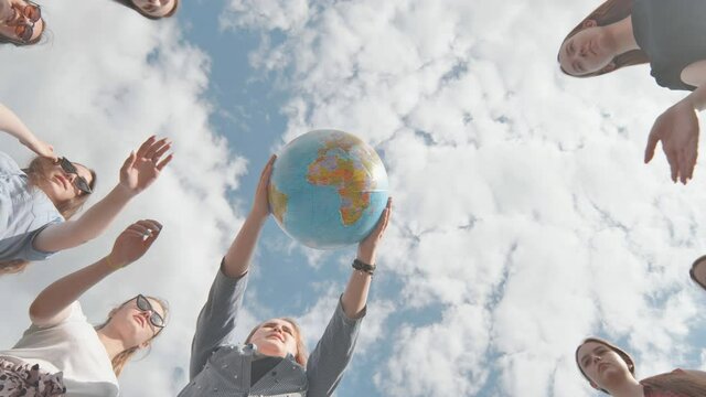 Earth conservation concept. 11 girls hug the earth globe with their hands.