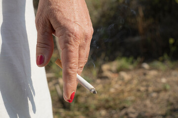 Elderly woman hold burning cigarette while smoking,tobacco smoke,unhealthy lifestyle