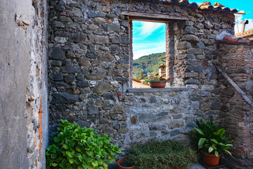 Blick durch eine alte Mauer in der Altstadt von Barga Toskana auf die umgrenzende Berglandschaft.
