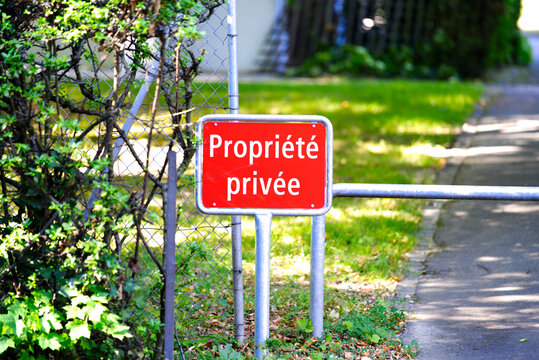 Red sign with text private property in front of apartment building on a sunny summer day. Photo taken August 28th, 2021, Geneva, Switzerland.